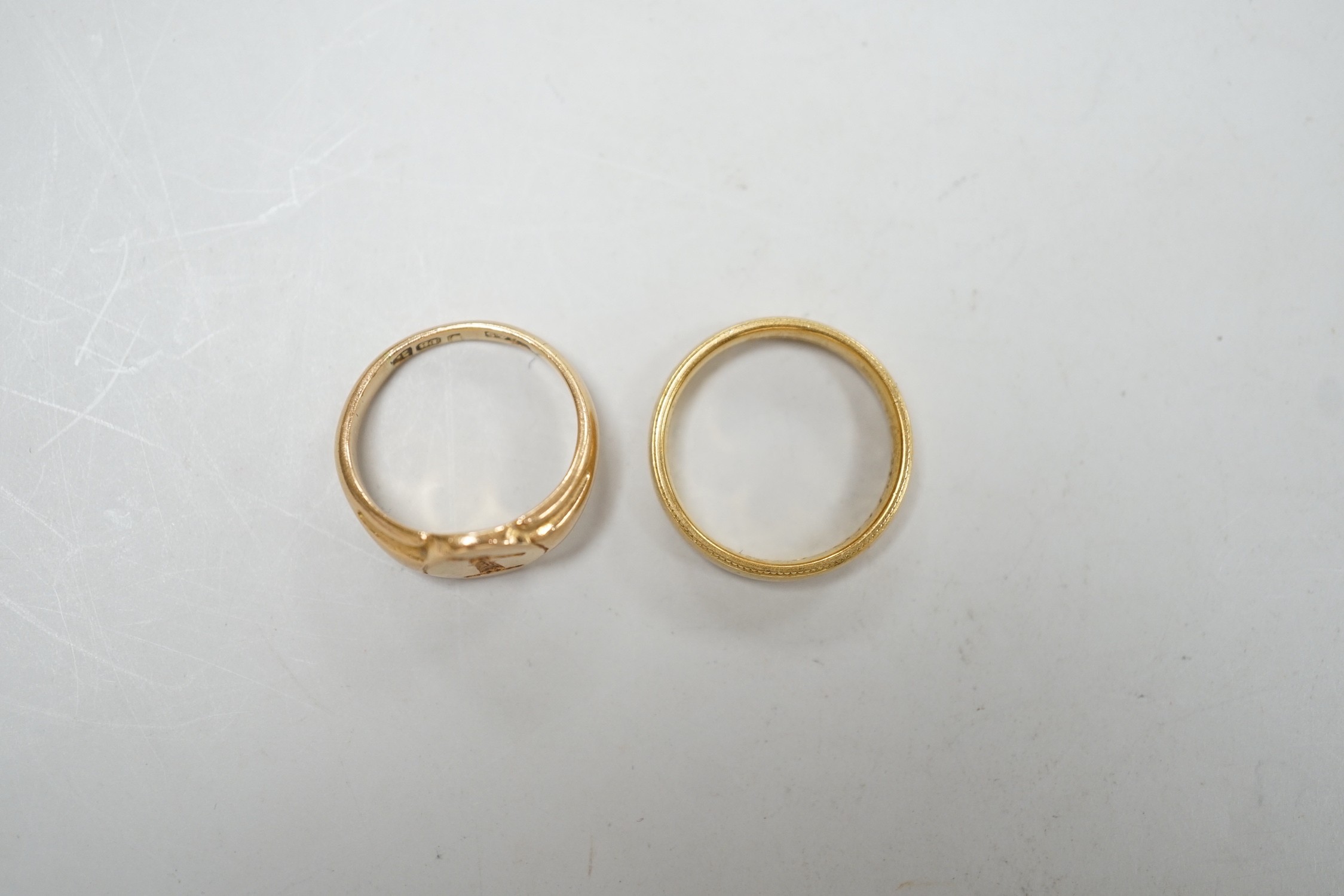 An early 20th century small 18ct gold signet ring, engraved with armorial, size G/H and a modern 18ct gold band, size I, with engraved inscription, 7.6 grams.